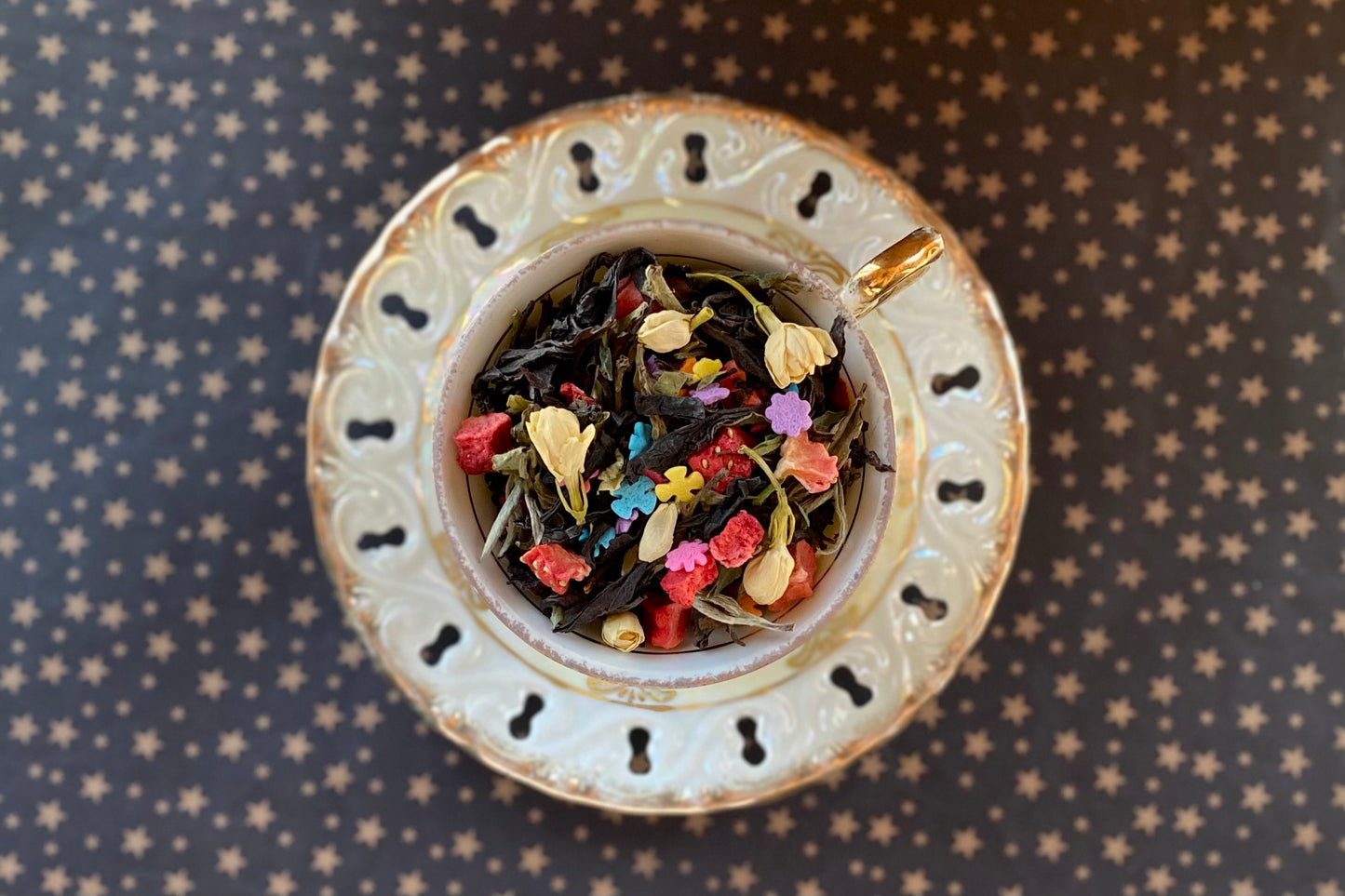Teacup full of oolong, strawberry, jasmine flowers and rainbow star sprinkles