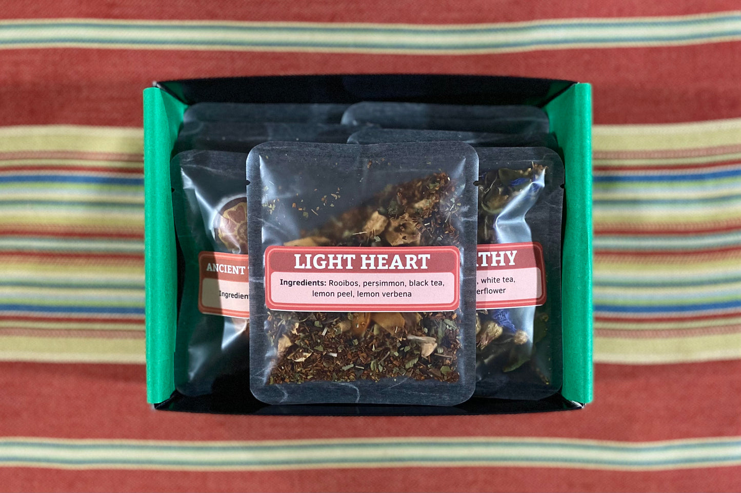 Seven Avatar-themed tea samples in a black box on a colorful cloth