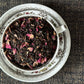teacup full of black tea, green chili flake and rose petal