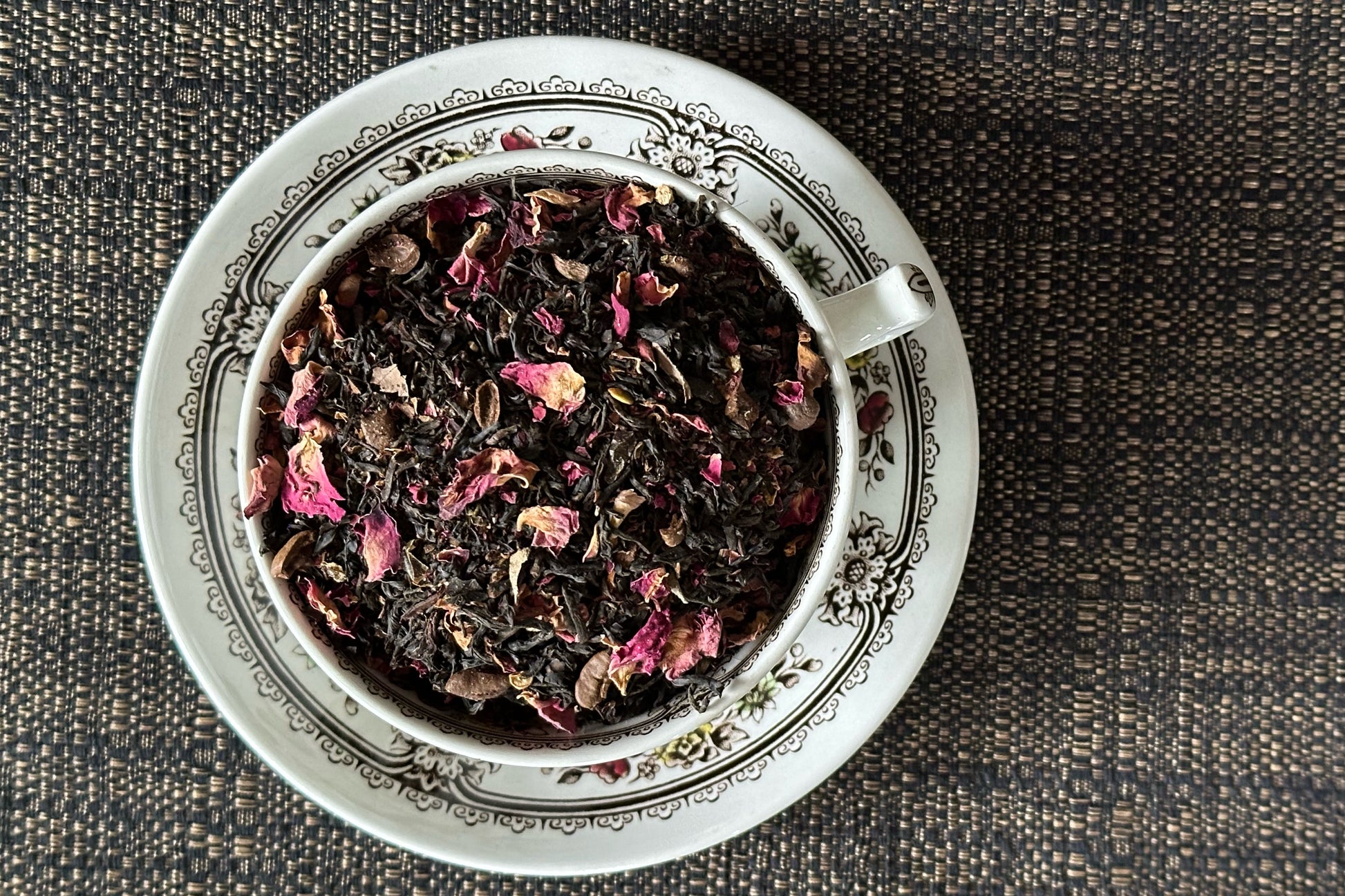 teacup full of black tea, green chili flake and rose petal