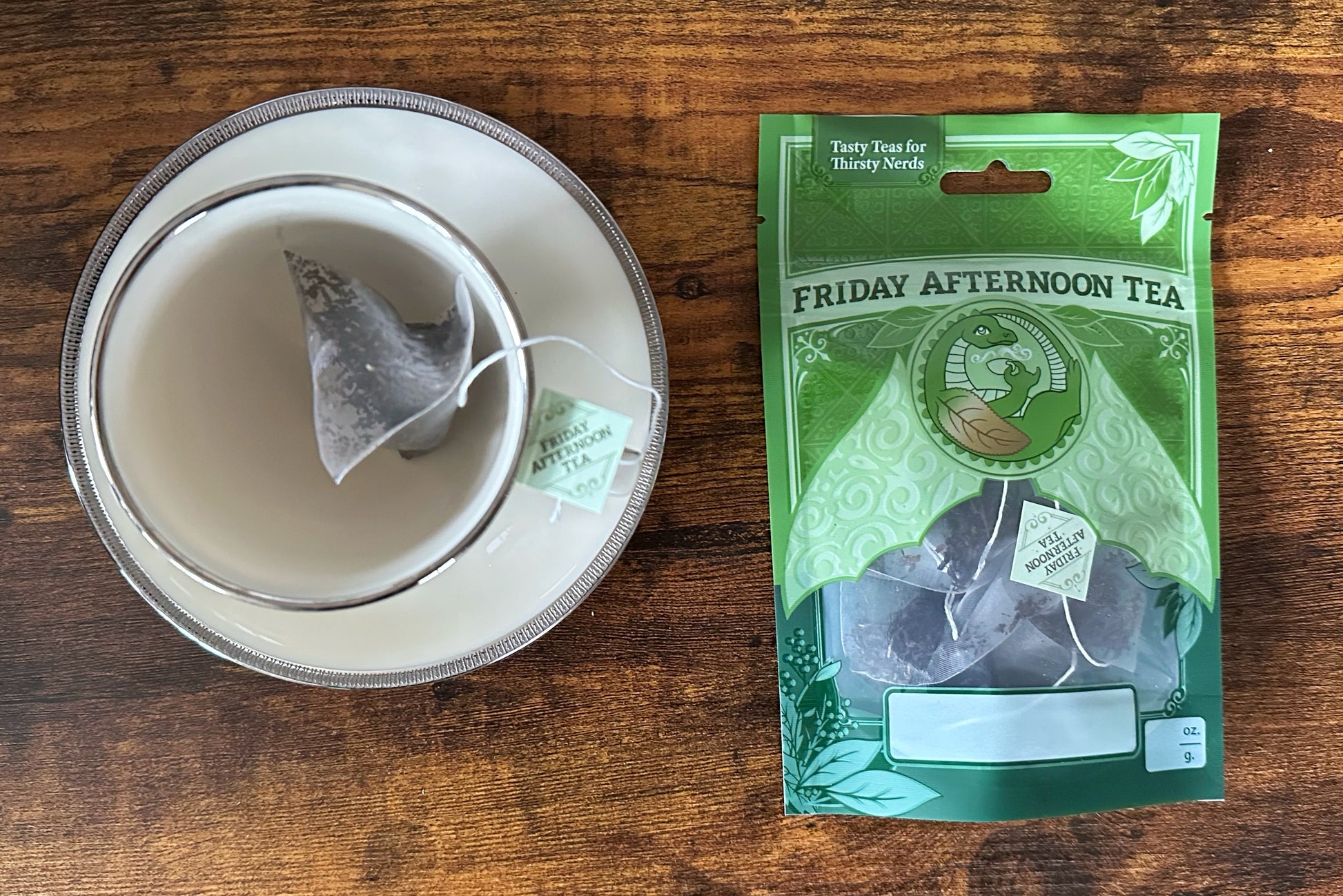 A pyramid teabag in a teacup beside a pouch of teabags