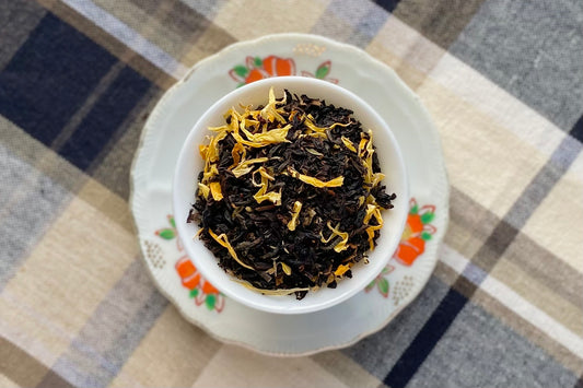 Teacup of black tea with yellow marigold leaf
