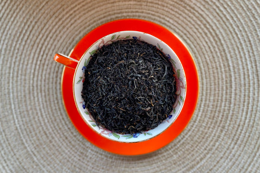 An orange teacup full of black tea