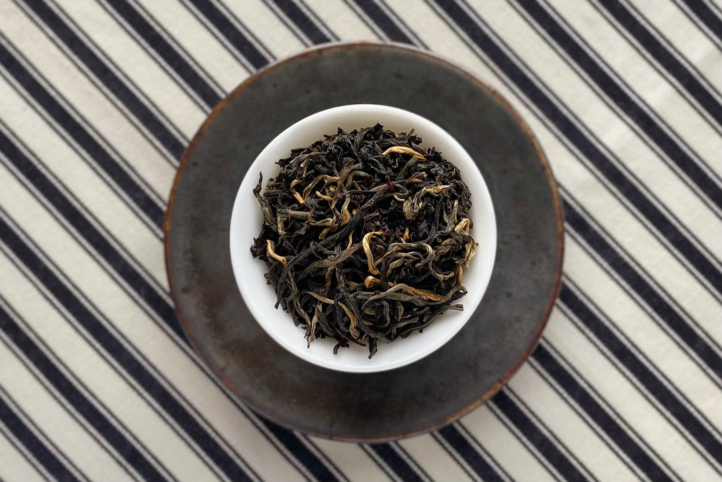 Teacup full of black tea with some gold tips