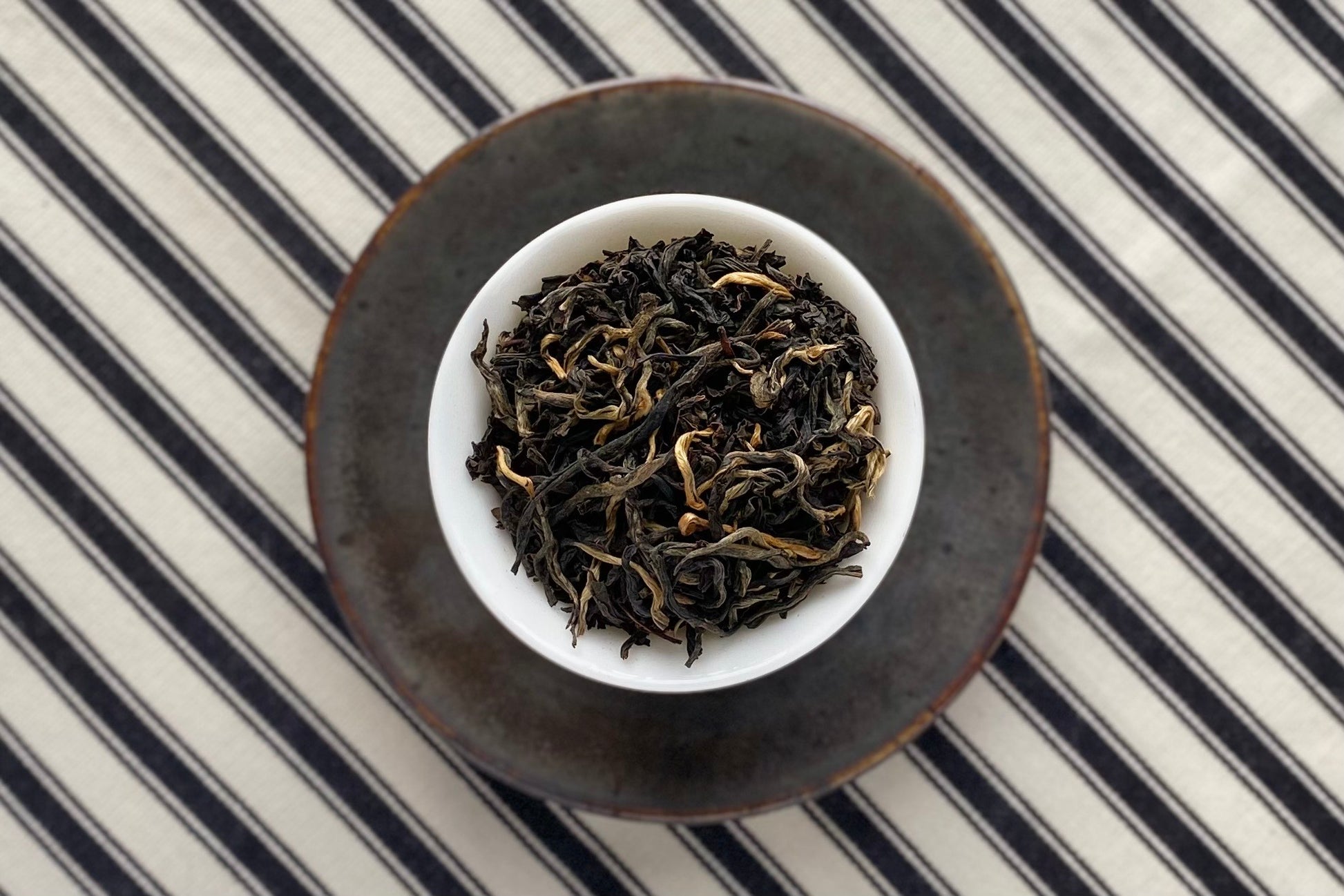 Teacup full of black tea with some gold tips