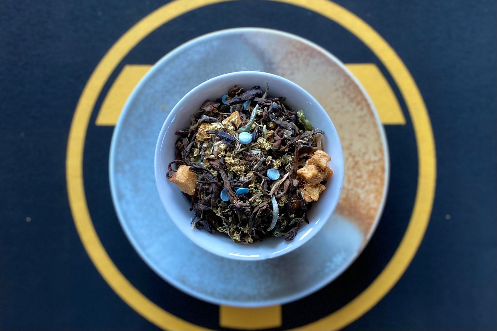 Teacup full of dark tea with apple, blue sprinkles and flowers